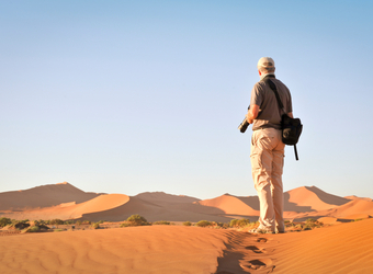 A visitor and photographer overlooks the vast sand dune plains looking for the right shot in Sossusvlei, Namibia