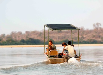 Safari guests motor along in a motorboat along the Rufiji River in search of animal sightings in the Selous Game Reserve, Tanzania