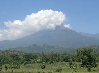 A cloud covers the top of Mount Meru, and the jungle area surrounding the peak is lush and green from rain in Arusha, Tanzania