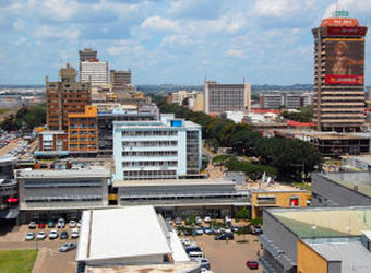 Downtown Lusaka with few high rise buldings but one large poster is vibrantly filled with a multitude of cars in Zambia